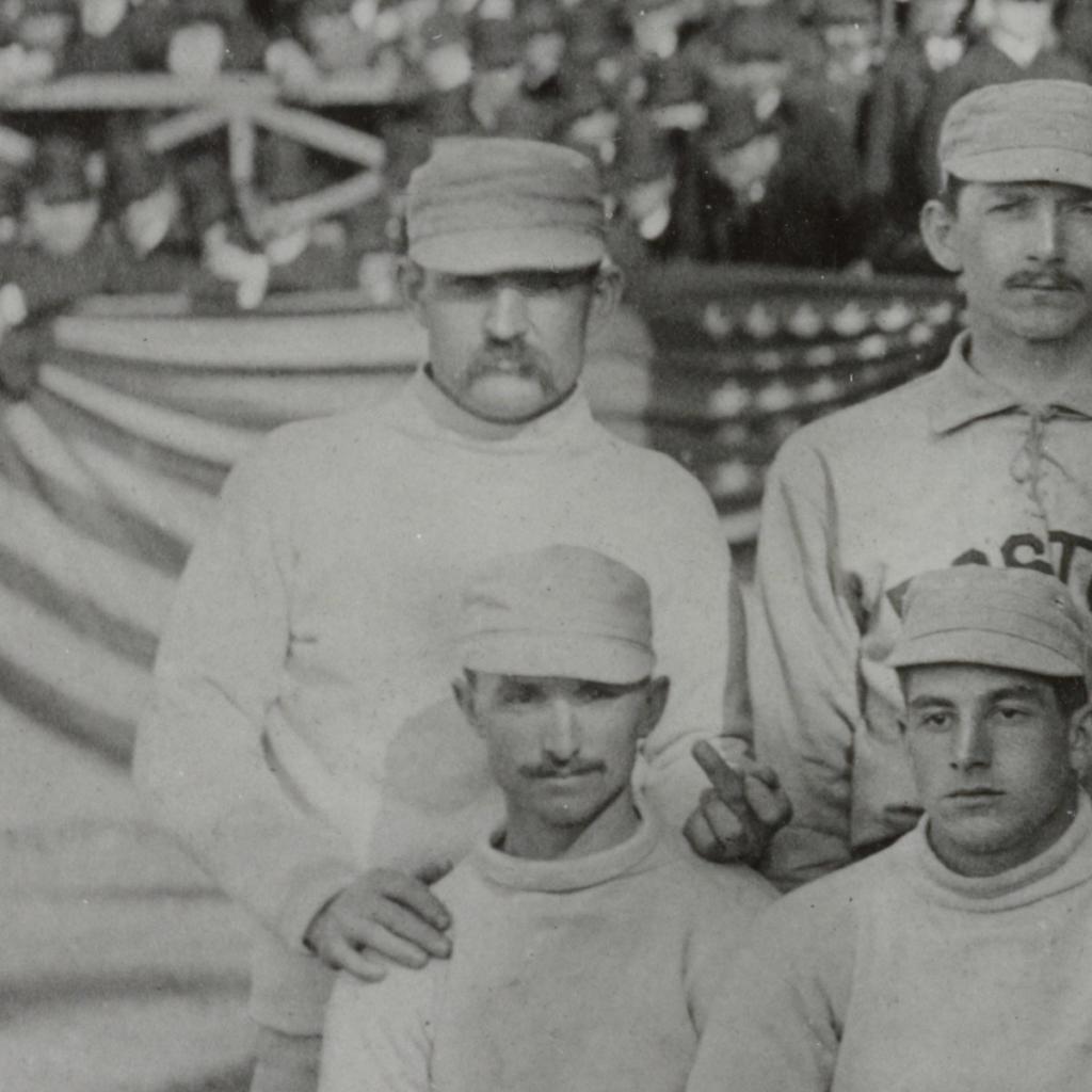 Charles "Old Hoss" Radbourne med Boston Beaneaters viser fingeren til kameraet under et lagbilde før en kamp mot New York Giants på åpningsdagen, cirka 1886. — Old Hoss Radbourn finger.jpg (29. april 1886) av F.L. Howe, fotograf., CC-PD-Mark.